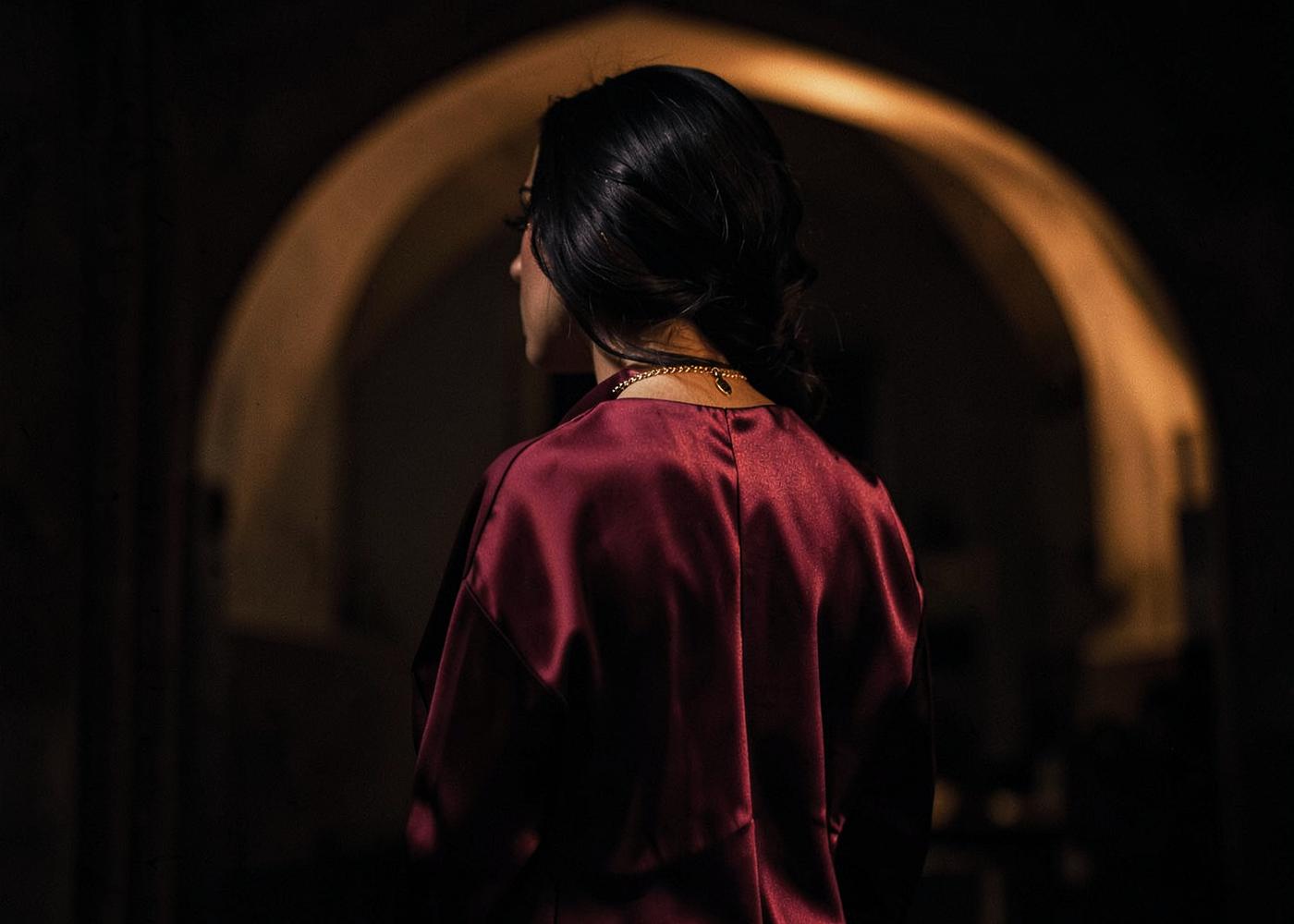 Mulher de vestido vinho em ambiente de luz quente, Templo das Deusas